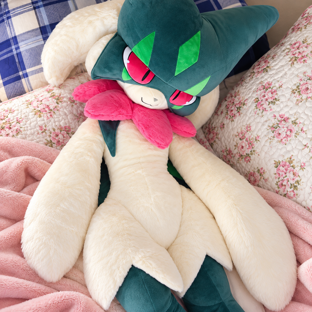 Pokemon Meowscarada Plush Pillow Stuffed Toy A large plush toy of a dark teal and cream creature with bright pink accents, resting on a bed with floral pillows and a pink blanket.