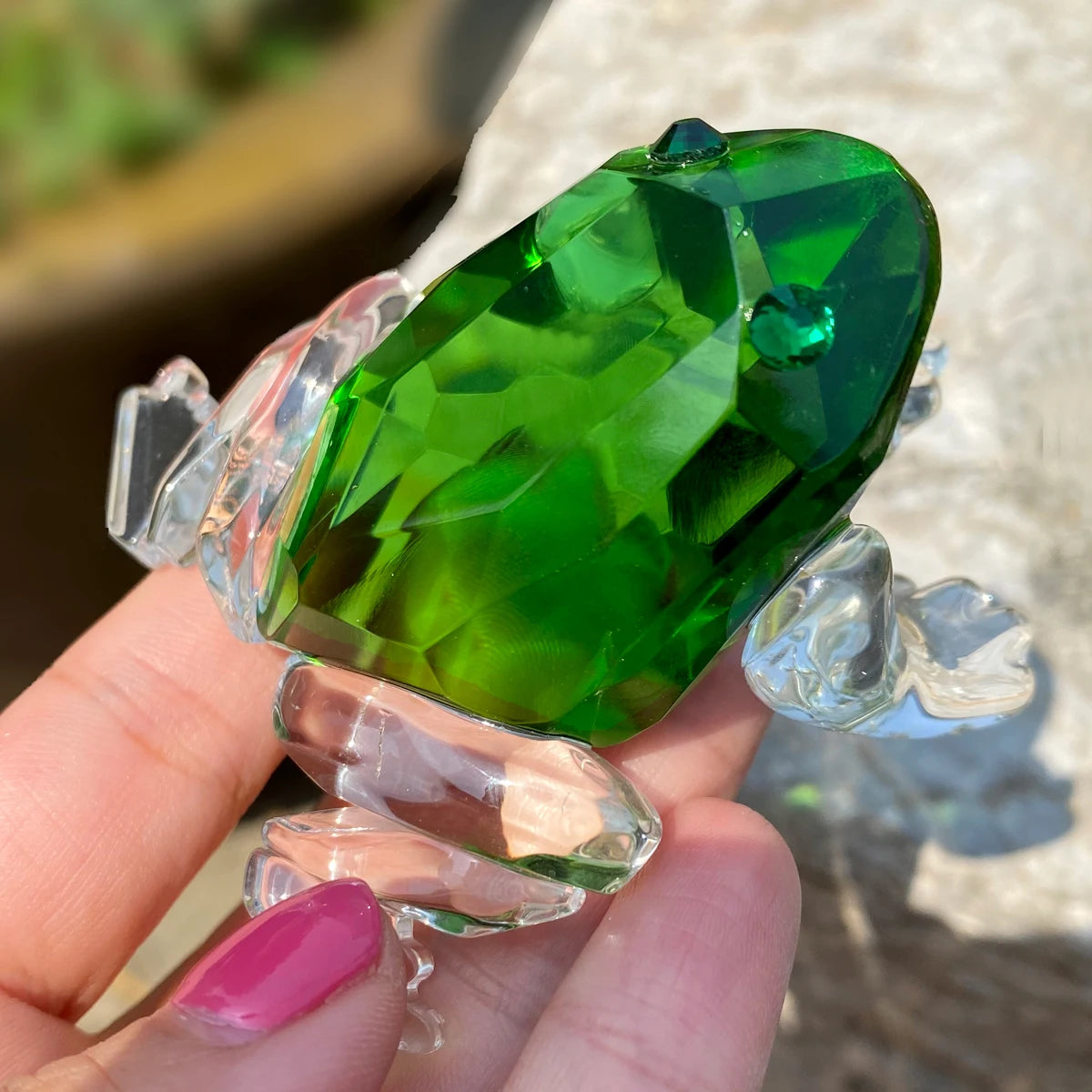 Crystal Glass Frog Figurine – Vivid Animal Paperweight Table Ornament Green crystal held by a hand with pink nail polish, outdoor background