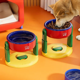Dog eating from a red and blue elevated food bowl on an orange floor.