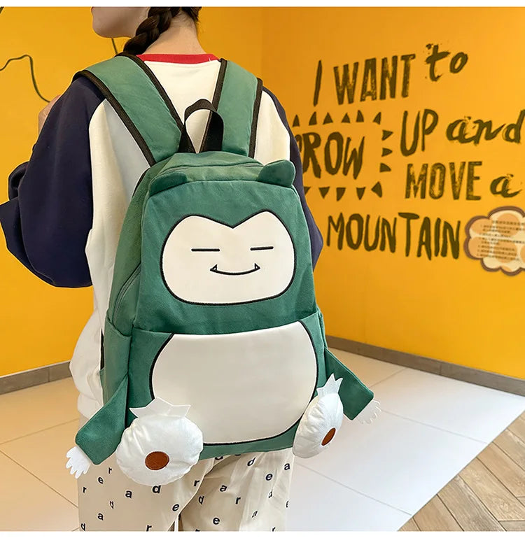 Snorlax Pokemon Backpack Large Capacity Casual Bag A person wearing a green and white cartoon-style backpack with plush character details, photographed from the back against a bright yellow wall with black text.