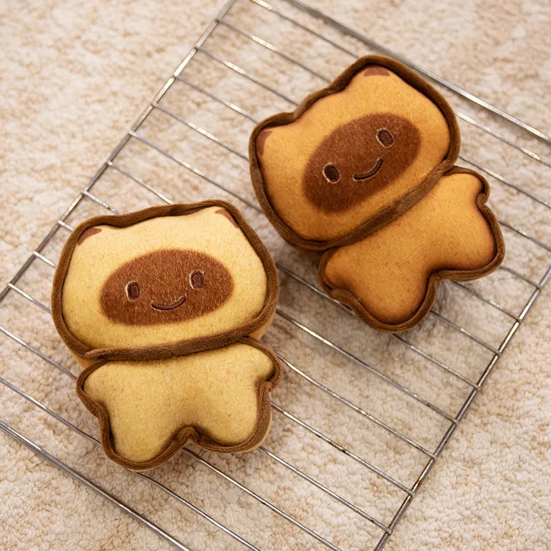 Capybara Bread Pillow – Cute Toast Plush Cushion Two cute, cartoonish cookies shaped like characters on a cooling rack.