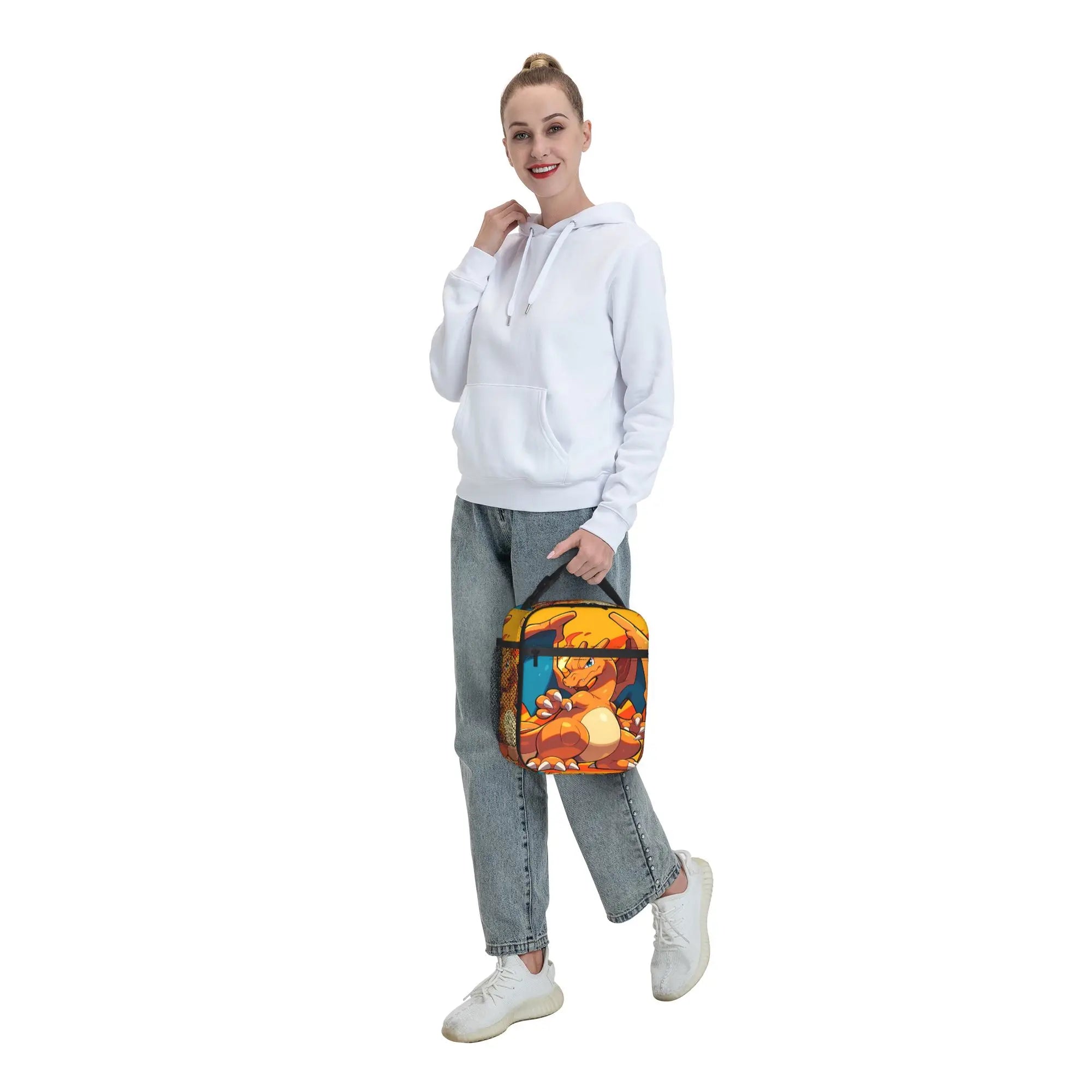 Pokemon Charizard Fire Burst Lunch Bag – Waterproof Insulated Tote A woman modeling a small insulated tote bag with a colorful cartoon bear print, styled with a white hoodie, light blue jeans, and white sneakers against a plain white background.