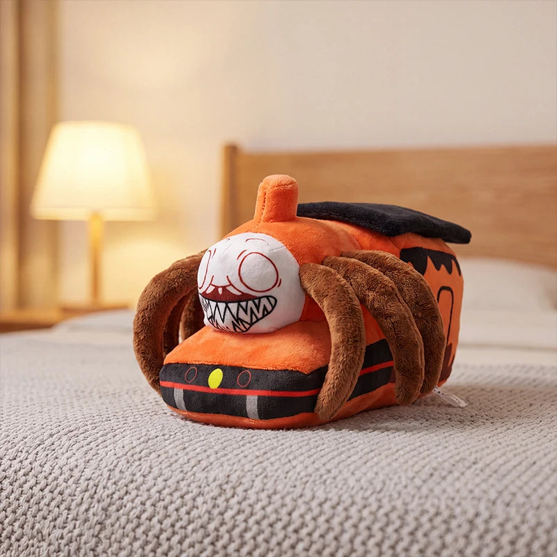Horror Spider Plush Dolls – 2-Piece Creepy Halloween Set An orange plush toy shaped like a monster train or vehicle with brown spider-like legs, a black top, and a white face with sharp teeth, resting on a bed in a softly lit bedroom.