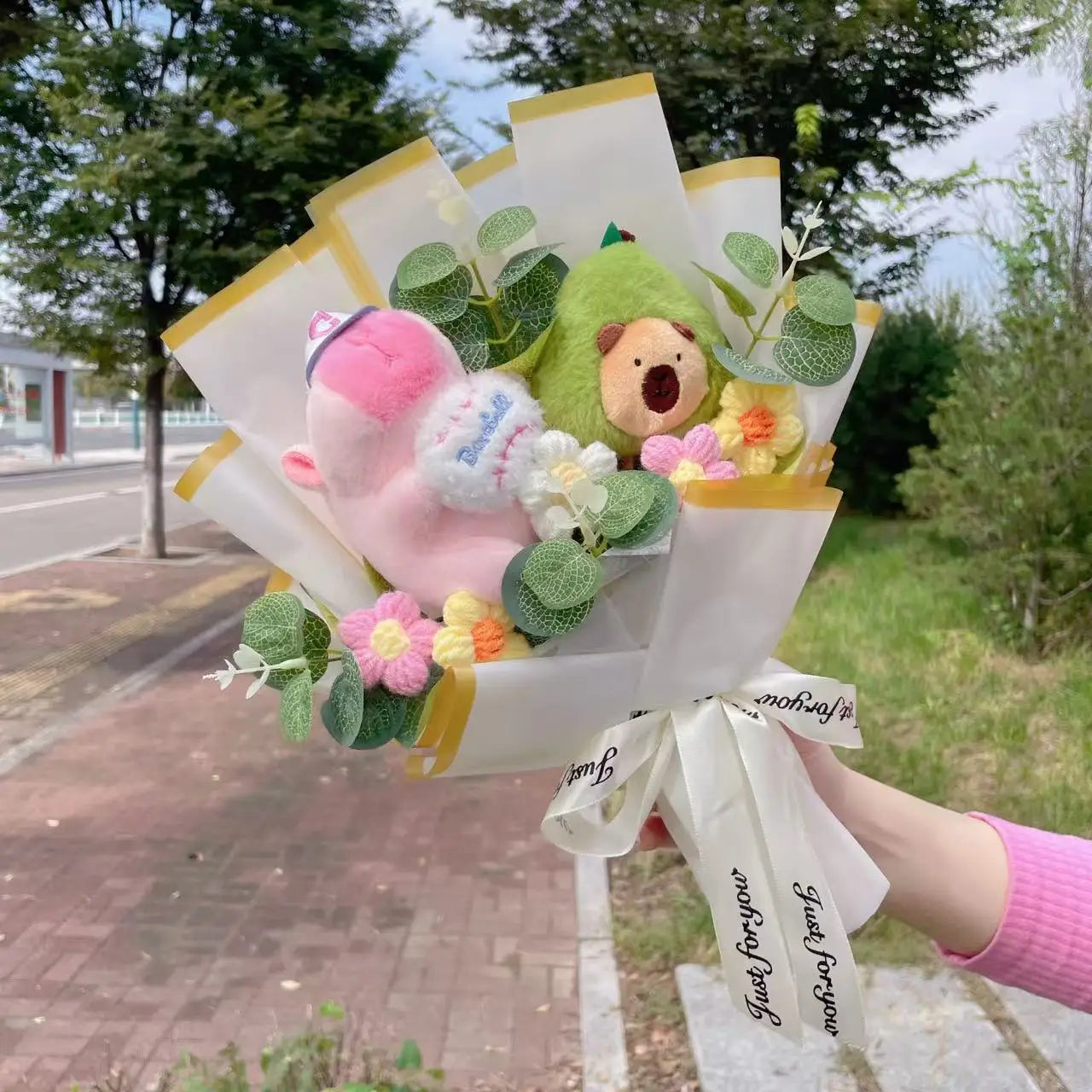 Capybara Plush with Crochet Flowers – Cute Flower Bouquet Gift Bouquet with plush toys and flowers held outdoors on a sunny day.