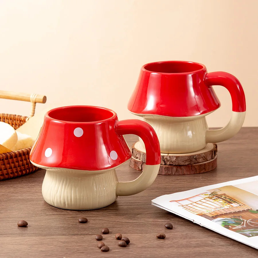 Premium Mushroom Coffee Cup – Large Ceramic Mug Two red and beige ceramic mugs shaped like mushrooms on a wooden surface with coffee beans and a magazine.