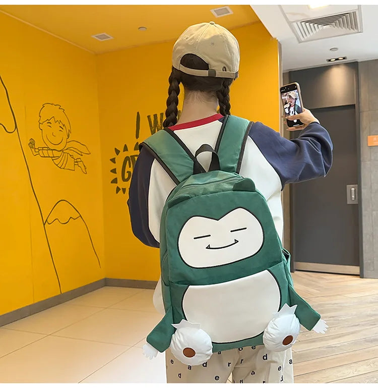 Snorlax Pokemon Backpack Large Capacity Casual Bag A person wearing a green and white cartoon character backpack, photographed from behind in a hallway with a bright yellow wall.