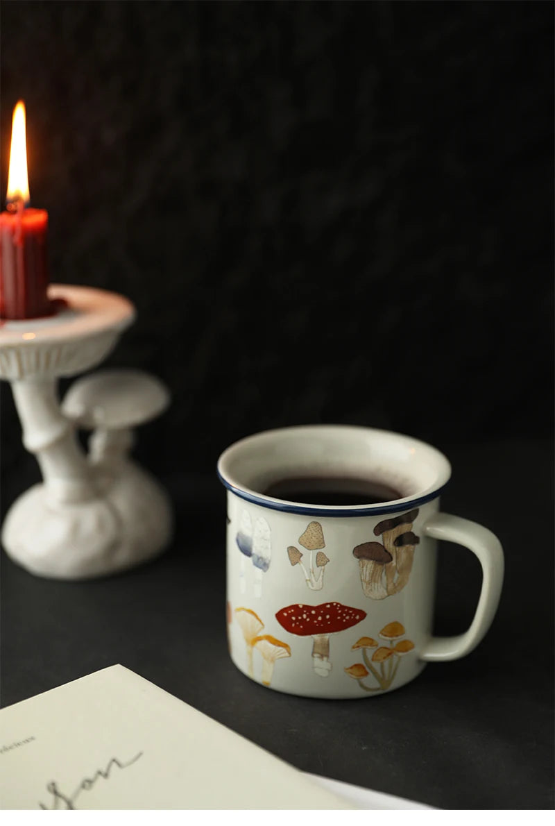 Mushroom Ceramic Coffee Cup – Japanese Cartoon Style Mug with cartoon designs on a dark surface next to a lit candle