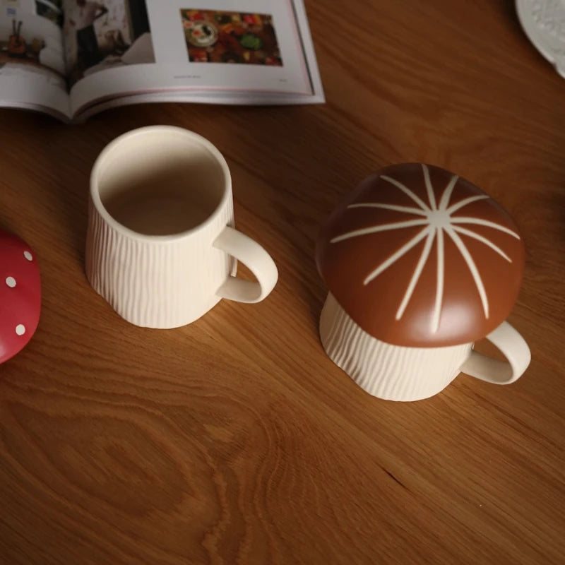 Mushroom Coffee Mug with Lid – Cute Drinking Cup Two ceramic mugs on a wooden surface with one having a lid.