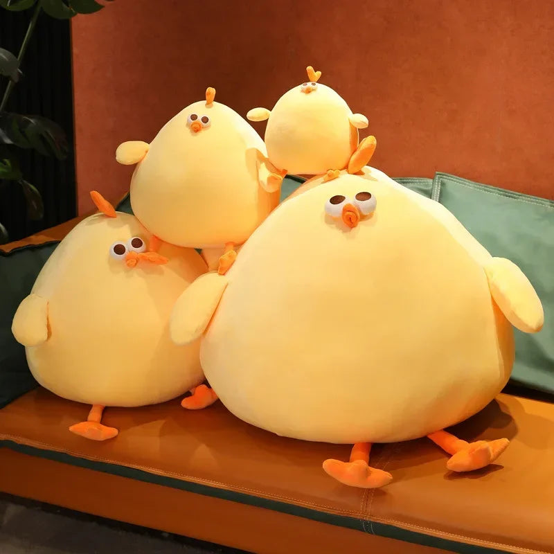 Squishmallow Fat Chicken Plush Toy Stuffed Animal Four yellow plush ducks with orange beaks and feet on a brown surface.