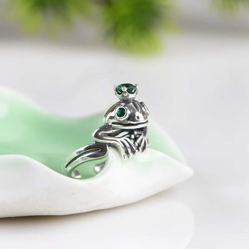 925 Silver Frog Crown Ring – Retro Adjustable Statement Jewelry Silver frog pendant with green gemstones on a white stone surface