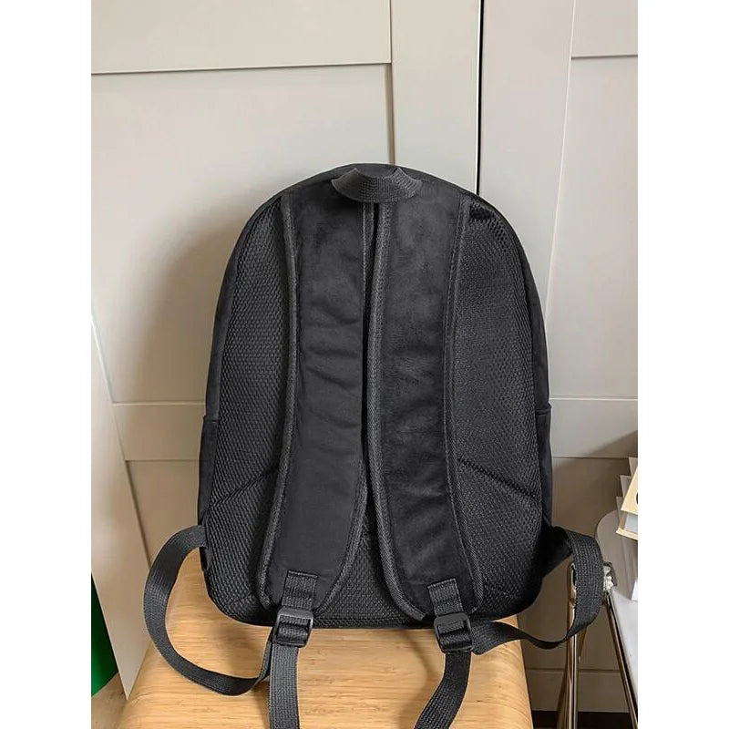Snorlax Pokemon Backpack Large Capacity Casual Bag A black mesh and fabric backpack shown from the back, resting on a light wood surface against a beige paneled wall.