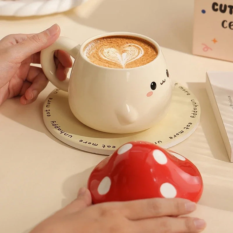 Cute Mushroom Coffee Mug with Lid – 400ML Ceramic Cup Cute mug with a heart-shaped foam and a red mushroom-shaped object on a light surface.