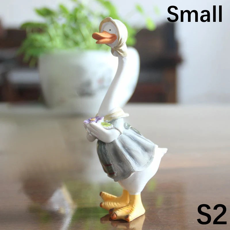 Resin Duck Family Garden Statue – Animal Outdoor Decor Sculpture Small figurine of a duck-like character holding a fish on a reflective surface with a blurred background.