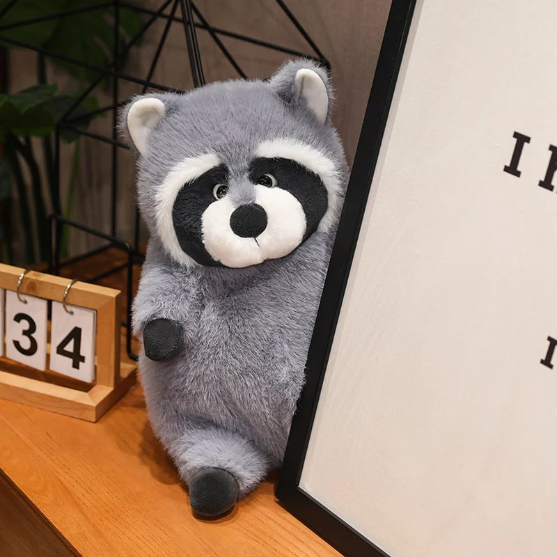 Squishmallow Grey Raccoon Plush Toy Stuffed Animal Plush raccoon toy on a wooden surface with a calendar in the background