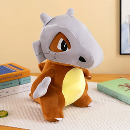 A Charmander plush toy sitting on a textured white blanket on a wooden table, with books in the background.