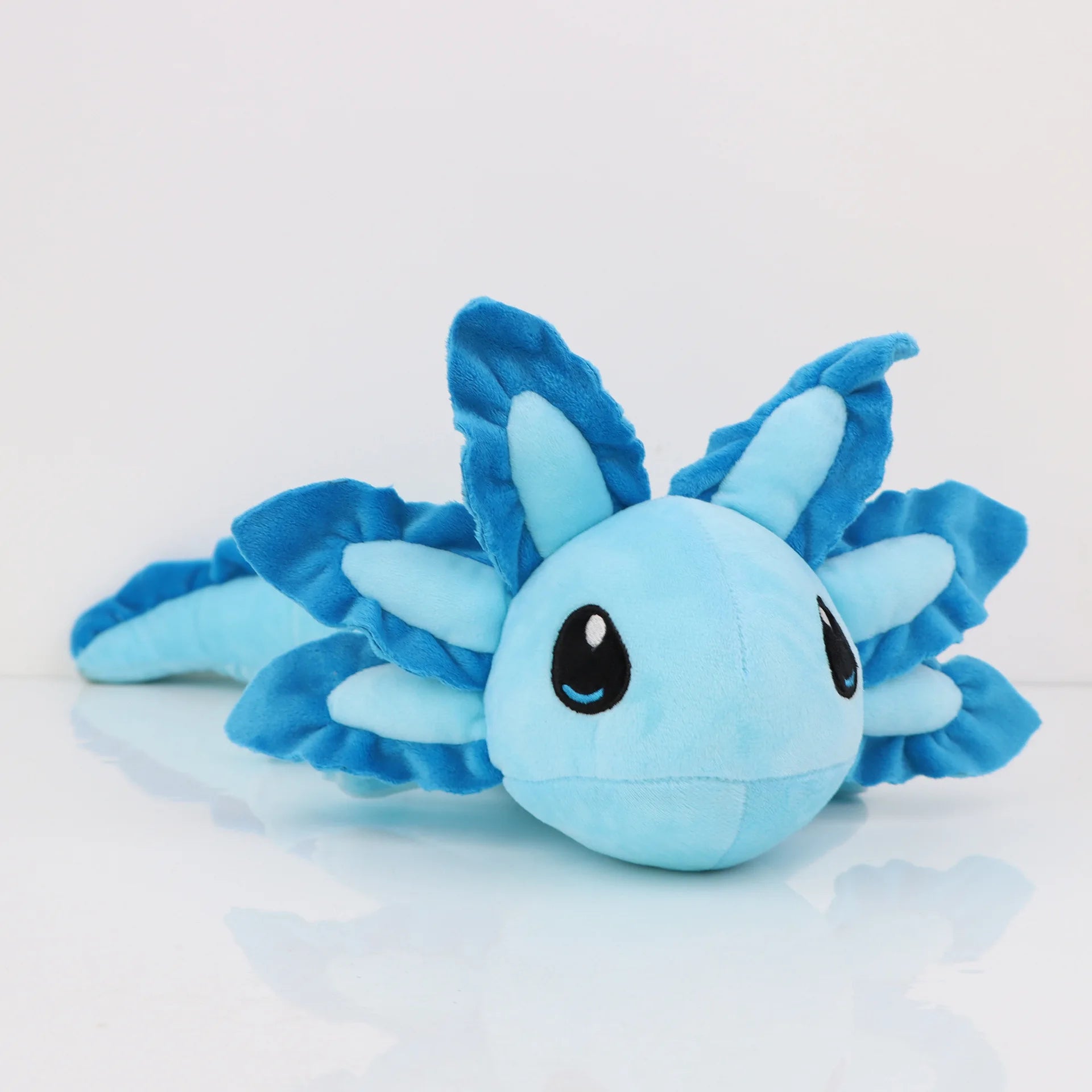 Axolotl Squishmallow Plush Toy – Soft Stuffed Animal Blue plush toy with a round body and leaf-like appendages on a light gray background