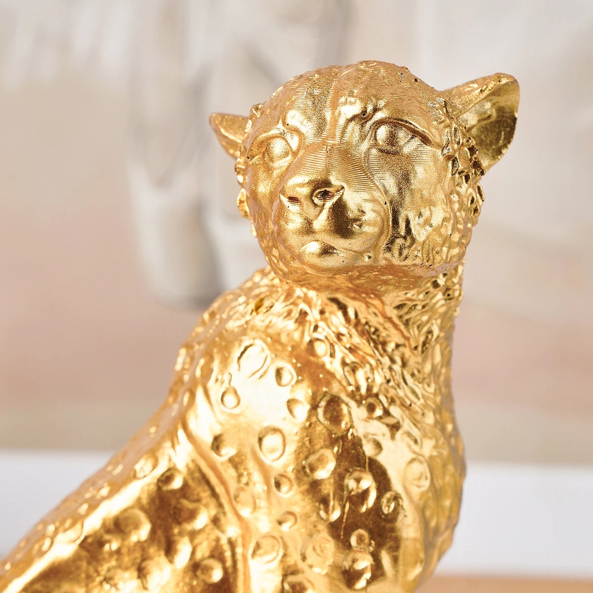 Golden Leopard Figurine – Resin Animal Desktop Decor Sculpture Gold panther figurine on a blurred background