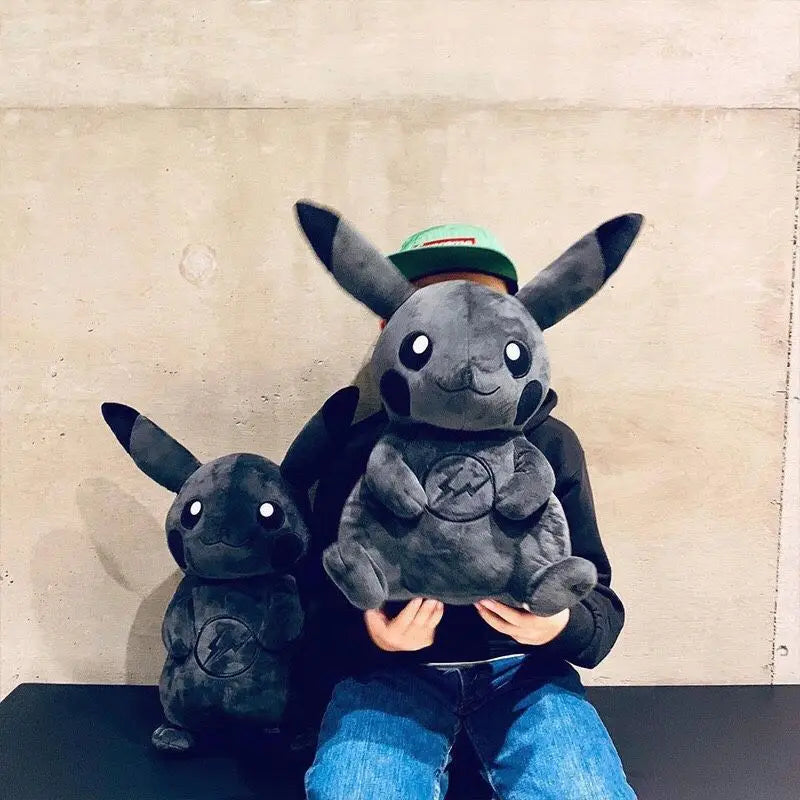 Dark Pikachu Plush Pillow Black Kawaii Doll Person holding a large plush toy of a gray creature with a smaller plush toy beside them against a plain background.