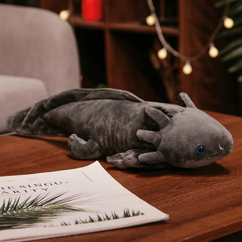 Cute Axolotl Plush Toy – Squishmallow Salamander Stuffed Animal Plush axolotl toy on a wooden surface with a magazine underneath, branded 'kawaiiies'.