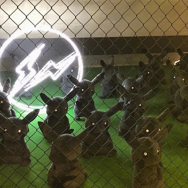 Dark Pikachu Plush Pillow Black Kawaii Doll Neon lightning bolt sign behind a chain-link fence with small figures on a green surface.