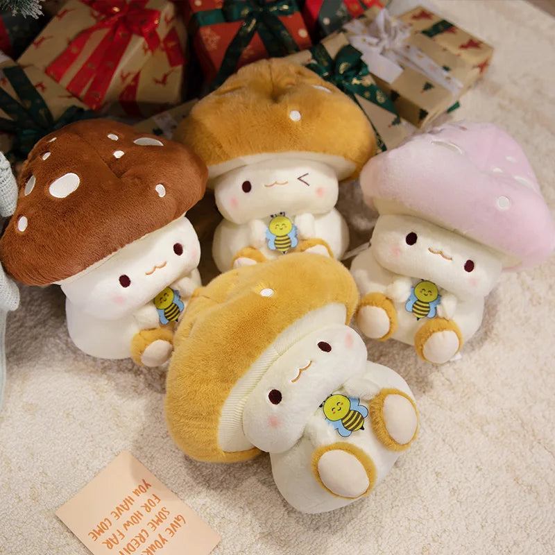 Creative Mushroom Plush Pillow – Cute Stuffed Plant Cushion for Home Décor Set of cute plush mushroom toys with a bee design on a soft surface with gift boxes in the background.