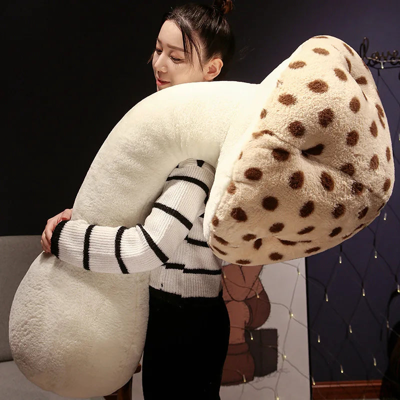 Large Mushroom Plush Pillow – Soft Huggable Stuffed Plant Cushion Person holding a large, soft, U-shaped pillow with a polka dot pattern.