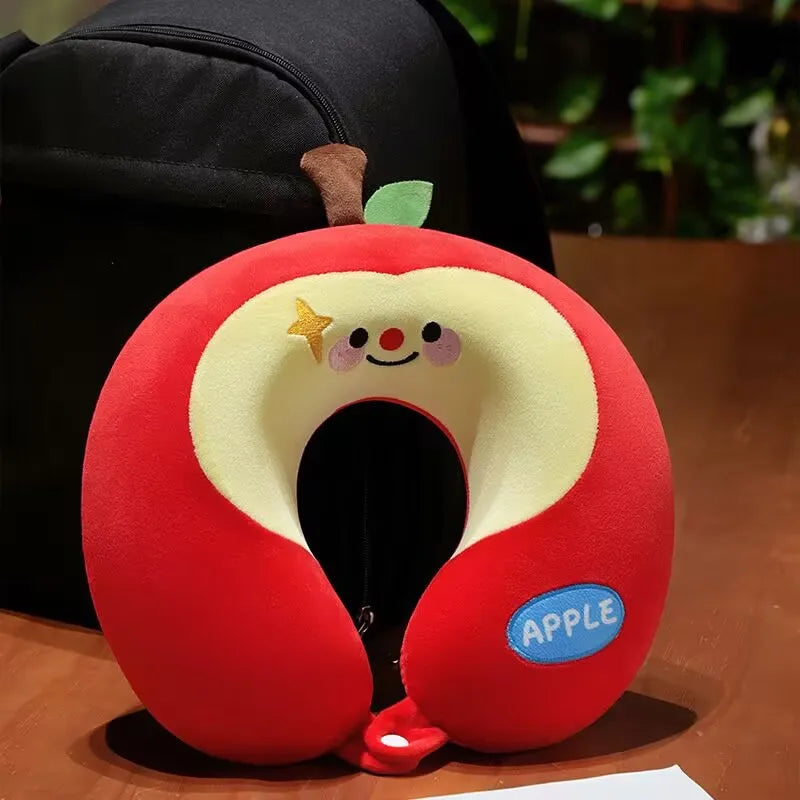 Cute Capybara U-Shaped Neck Pillow – Plush Travel Pillow Red apple-shaped neck pillow with a smiling face on a wooden surface.