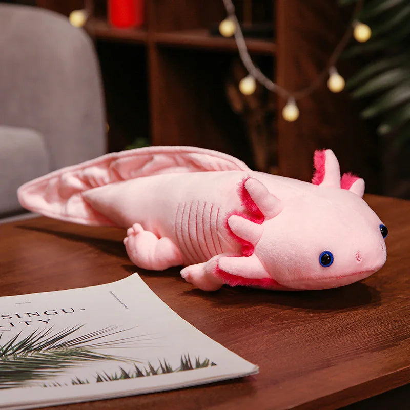 Cute Axolotl Plush Toy – Squishmallow Salamander Stuffed Animal Pink axolotl plush toy on a wooden table with a magazine underneath