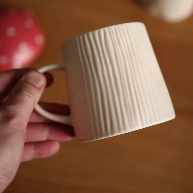 Mushroom Coffee Mug with Lid – Cute Drinking Cup White textured mug held by a hand against a blurred background