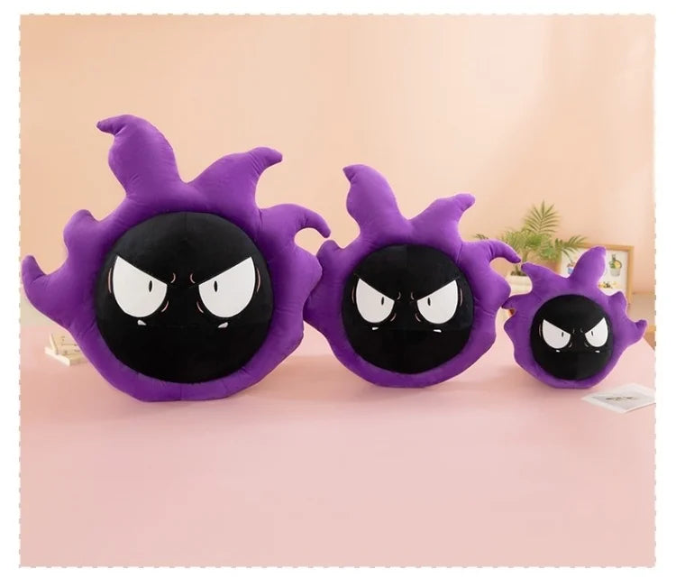 Pokemon Gastly Plush Pillow Stuffed Toy Three purple and black ghost-shaped plush pillows of different sizes arranged on a pink surface against a soft pink background.