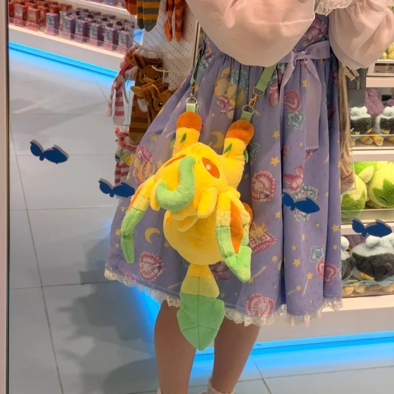 Pokemon Eevee Evolution Plush Crossbody Bag A yellow plush character bag with green leaf-like accents and orange horns, worn crossbody over a lavender patterned skirt in a retail store.