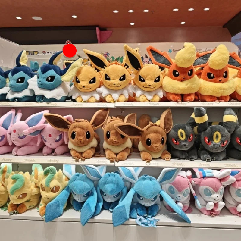 Pokemon Eevee Evolution Plush Crossbody Bag Three shelves filled with colorful plush toy Pokémon, including Eevee, Eevee variants, and other shiny-colored plushies, displayed in a store setting.
