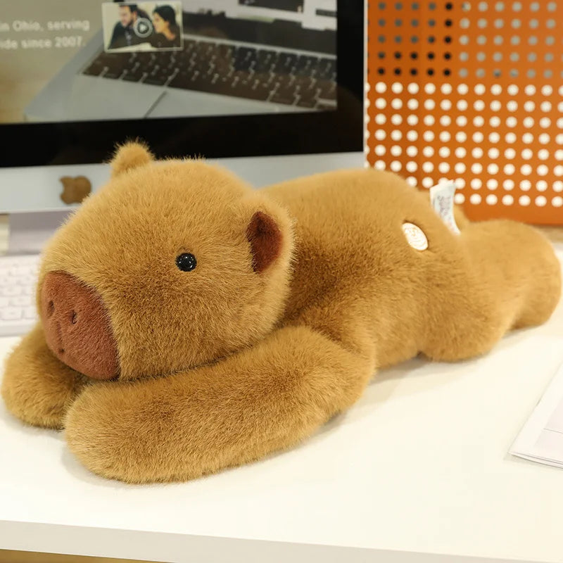 Weighted Capybara Plush Pillow – Soft Stuffed Animal Brown teddy bear plush toy on a desk with a computer monitor in the background