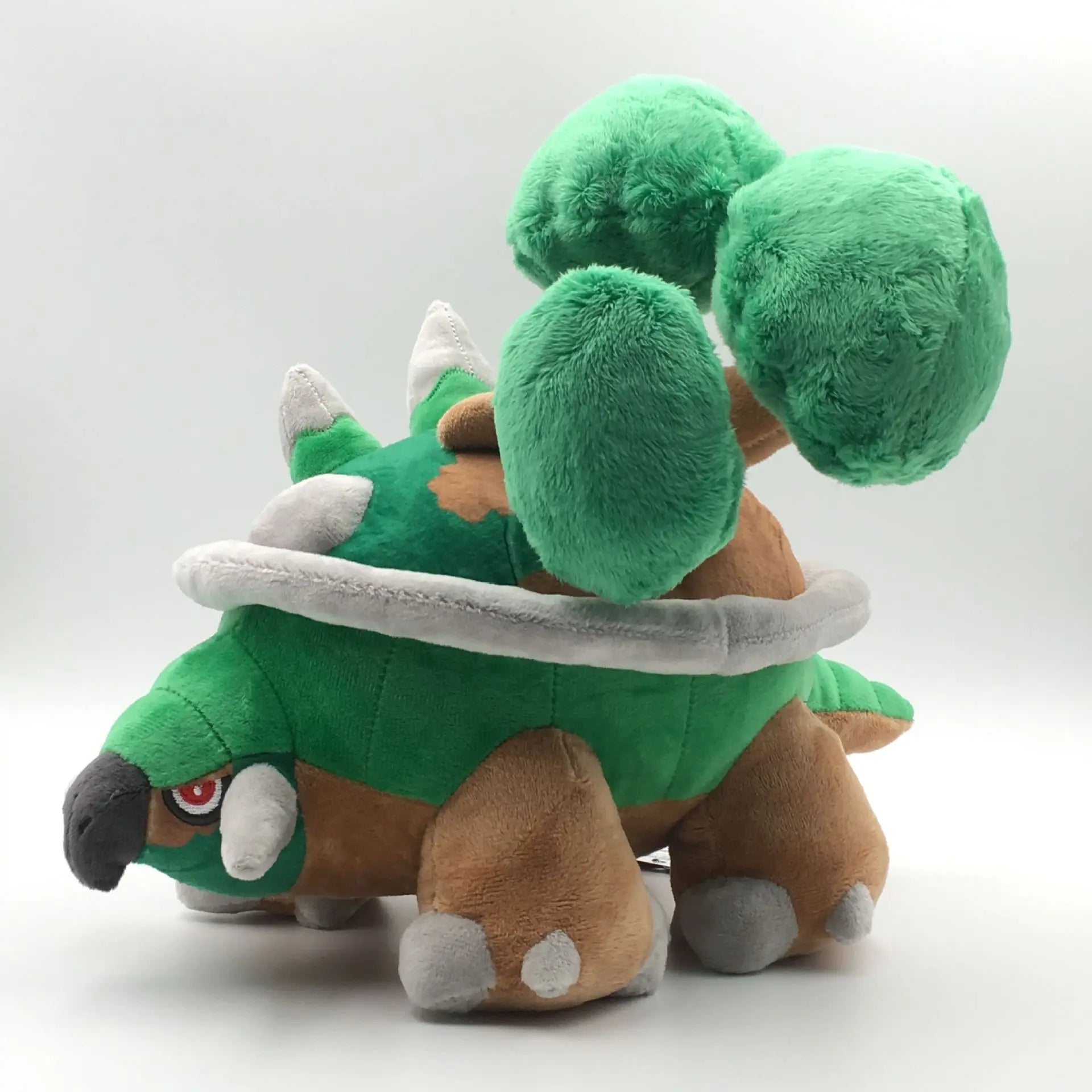 Pokemon Torterra Plush Toy – Turtwig Evolution Stuffed Doll A plush toy of a green and brown armored creature with three large green leaf-like structures on its back, photographed on a light gray studio background.