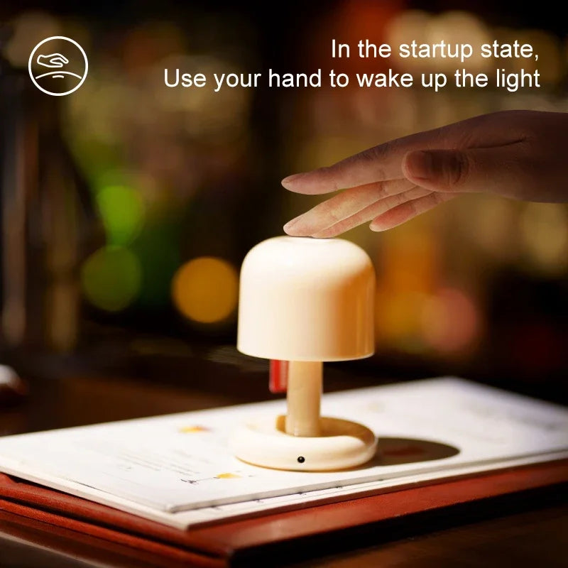 Orange Mushroom LED Night Light – Nordic Minimalist Table Lamp Hand interacting with a small lamp on a book, with text about using a hand to wake up the light.