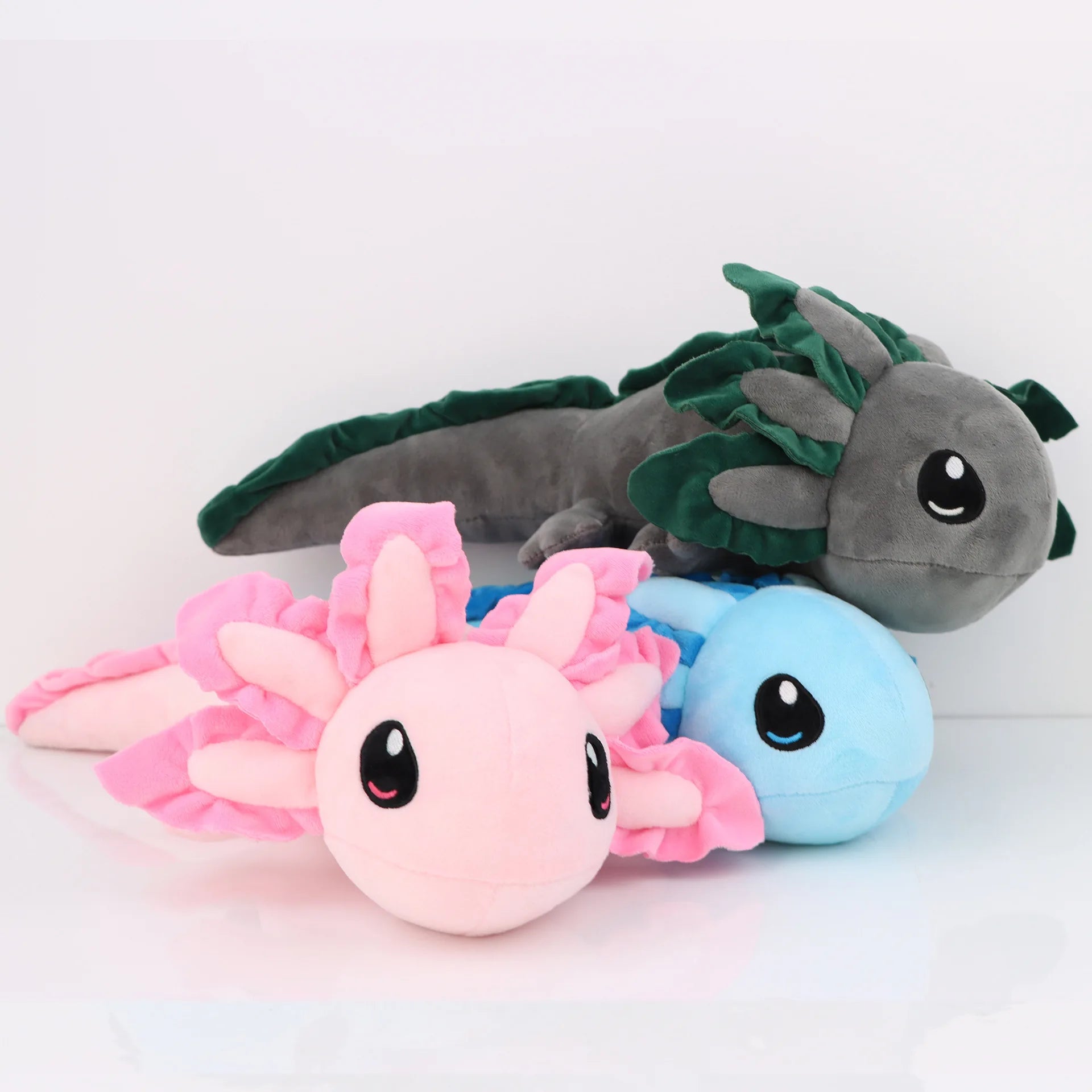 Axolotl Squishmallow Plush Toy – Soft Stuffed Animal Three axolotl plush toys in gray, pink, and blue on a white background