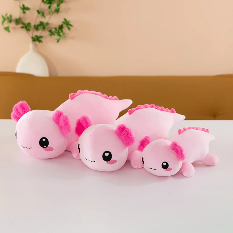 Axolotl Squishmallow Plush – Stuffed Animal Toy Set of pink axolotl plush toys on a white surface with a beige wall and plant in the background.