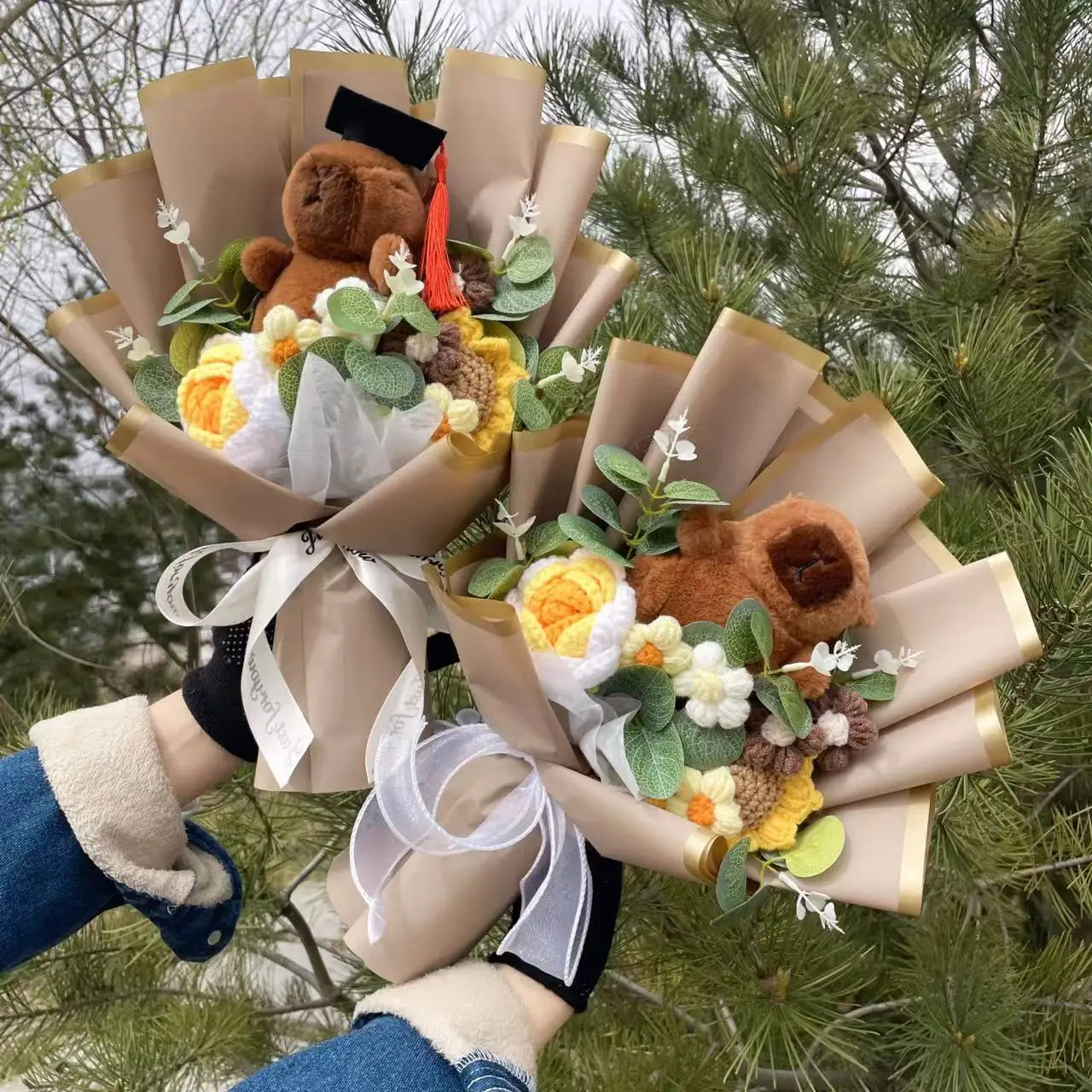 Capybara Plush with Crochet Flowers – Cute Flower Bouquet Gift Bouquet of flowers with a teddy bear wearing a graduation cap and gown, held against a green leafy background.