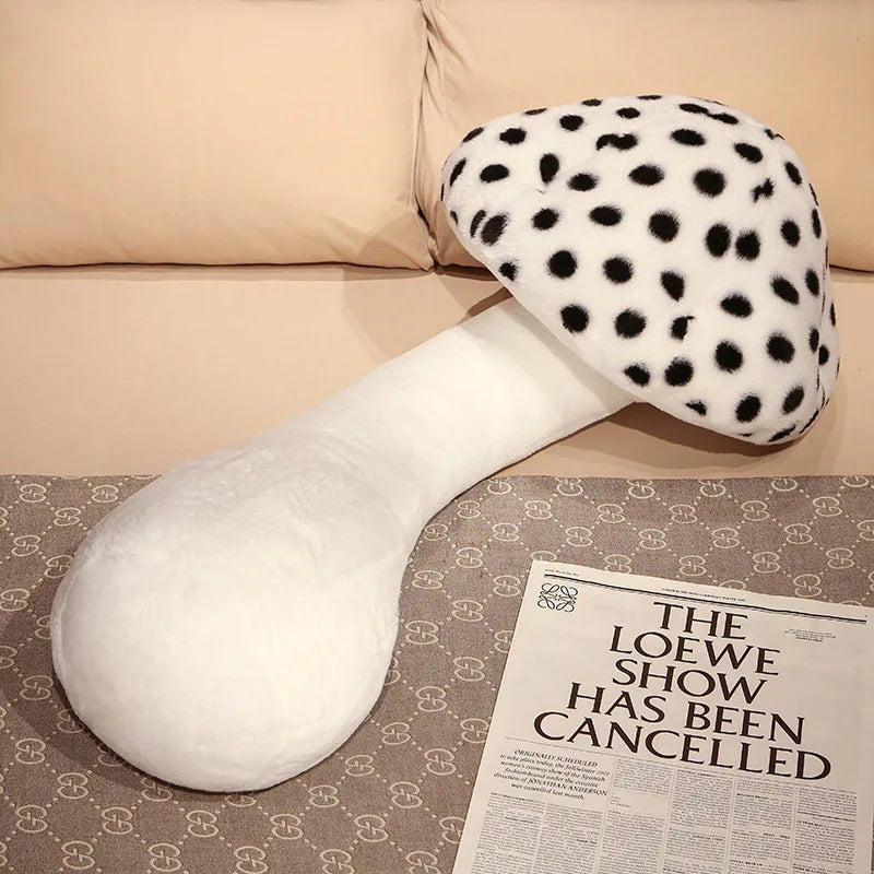 Large Mushroom Plush Pillow – Soft Huggable Stuffed Plant Cushion White and black polka dot mushroom-shaped pillow on a surface with a newspaper.