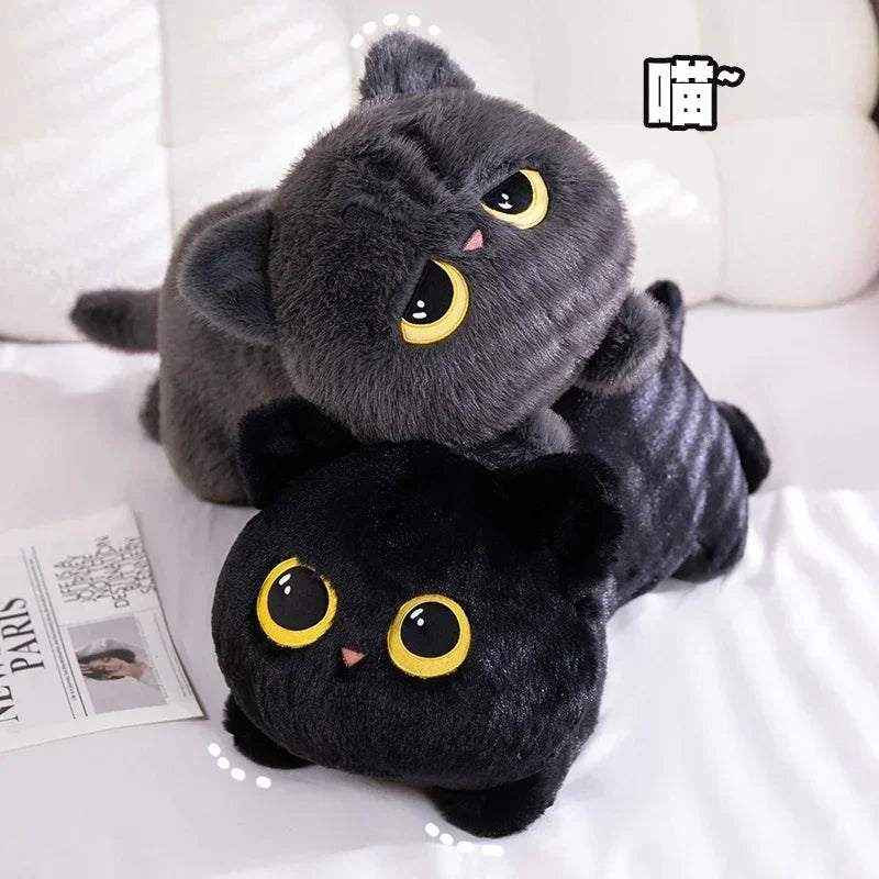 Black Cat Plush Pillow – Cute Kawaii Stuffed Animal Cushion Two plush cat toys with large yellow eyes, one dark gray and one black, posed together on a white bed with a magazine nearby.