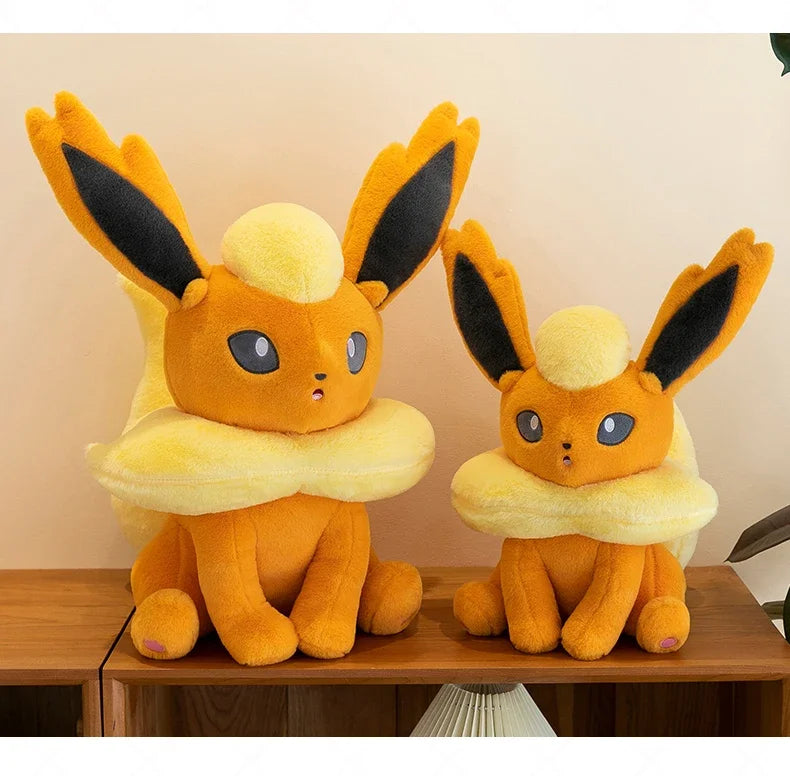 Pokemon Eevee Plush Toy – Vaporeon, Flareon & Jolteon Soft Stuffed Animal Two orange plush toys with large ears on a wooden surface.