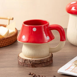 Red and white mushroom-shaped mug on a wooden coaster with a neutral background