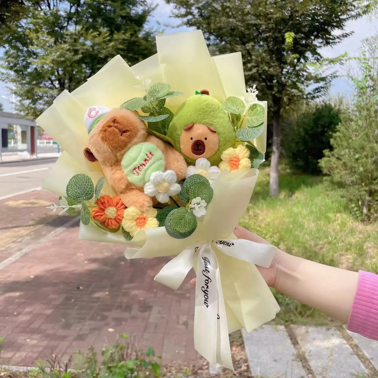 Capybara Plush with Crochet Flowers – Cute Flower Bouquet Gift Bouquet of plush toys and flowers held by a person outdoors.