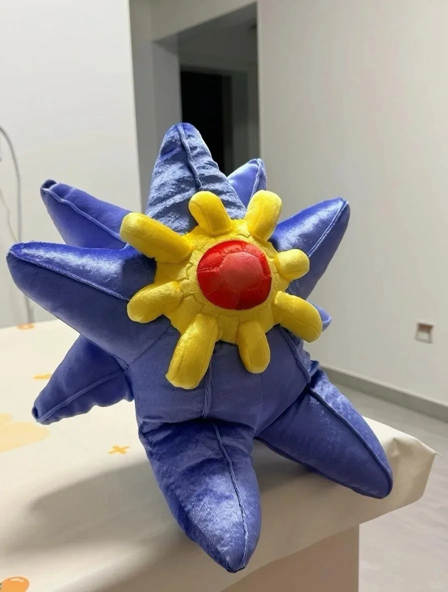 Pokemon Mega Plush Toy – Mega Lucario, Mega Greninja & Mega Starmie A plush starfish toy with a blue body, yellow rays, and a red center, displayed on a white surface in an indoor room.