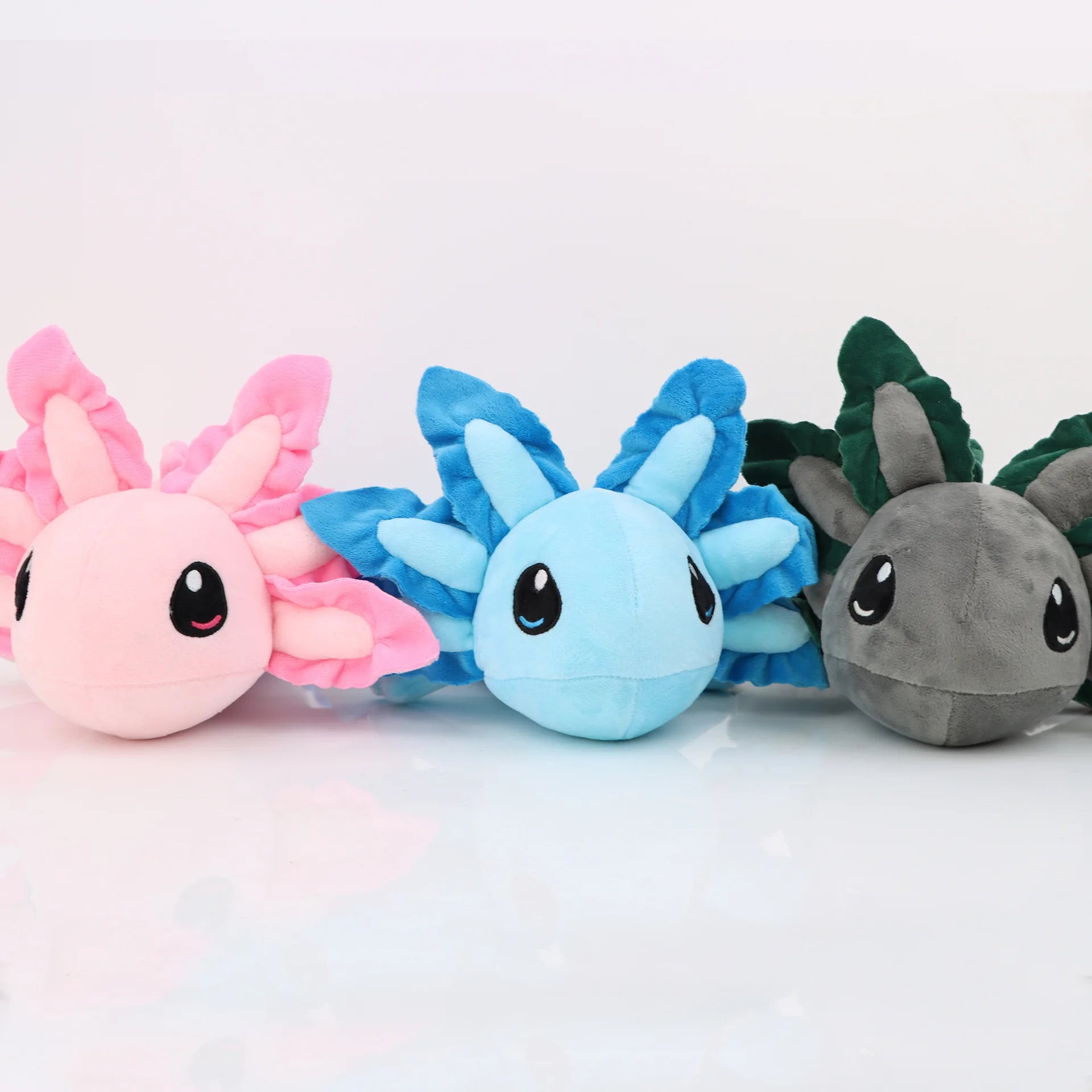 Axolotl Squishmallow Plush Toy – Soft Stuffed Animal Three colorful plush toys with different designs on a white background