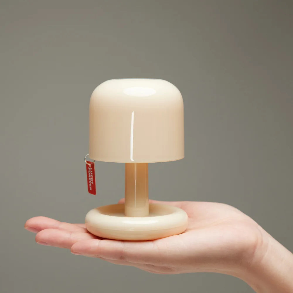 Orange Mushroom LED Night Light – Nordic Minimalist Table Lamp Small beige lamp held in a hand against a gray background