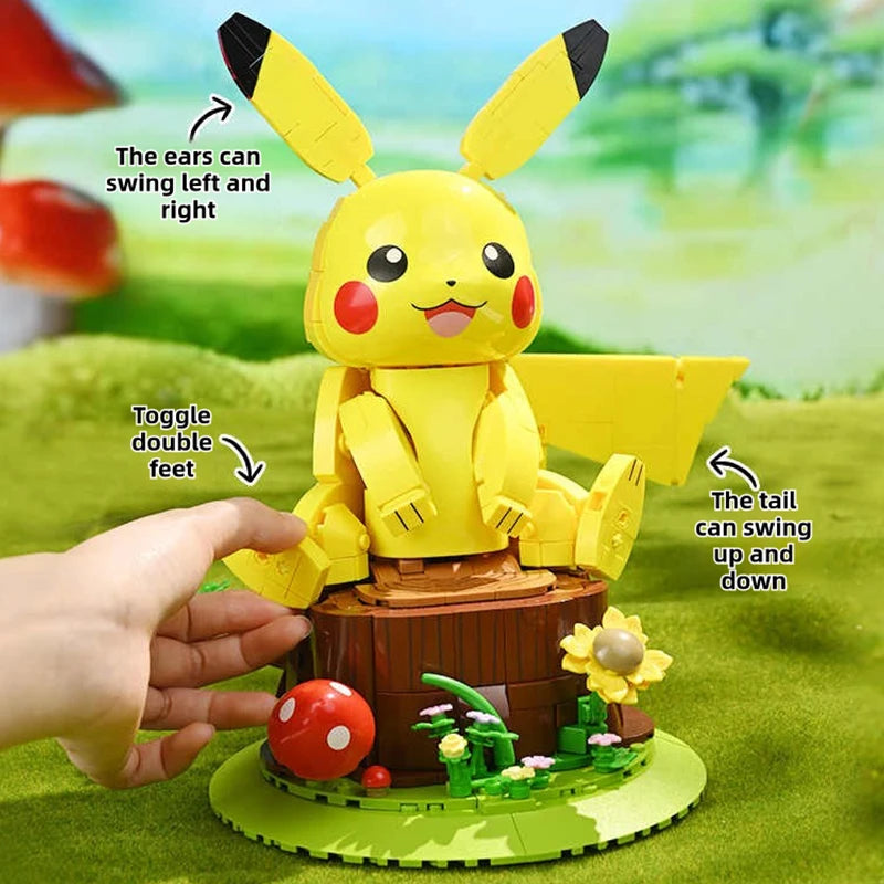 Pokemon Pikachu Building Blocks – DIY Model Brick Toy A yellow Pikachu-style building block toy sits on a green base with a brown log pedestal, shown with a human hand touching it. Text callouts describe interactive features: the ears can swing left and right, toggle double feet, and the tail can swing up and down.