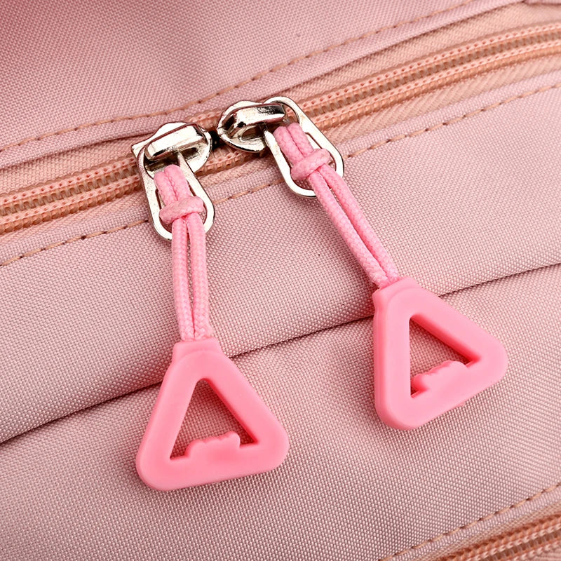 Capybara Bubble Tea Backpack – School Bag for Teens Close-up of a pink fabric zippered bag showing two matching pink silicone triangle zipper pull tabs with silver metal zipper pulls.