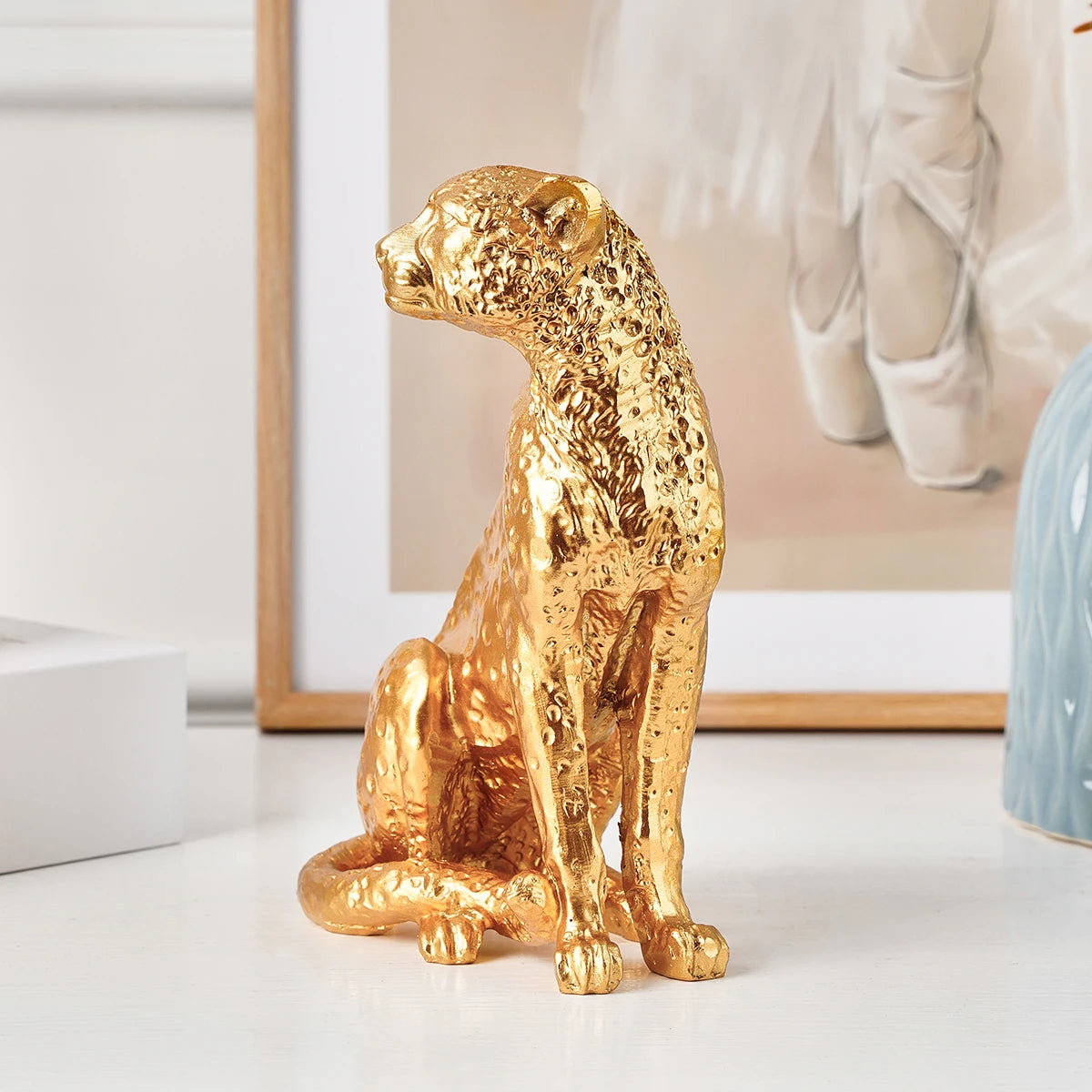Golden Leopard Figurine – Resin Animal Desktop Decor Sculpture Gold panther figurine on a white surface with a blurred background