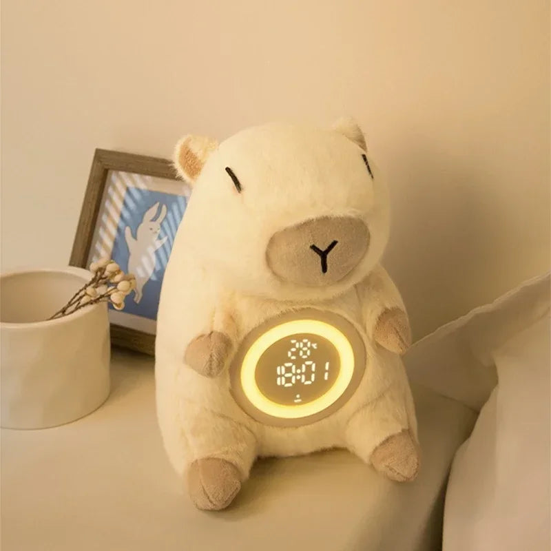 Capybara Plush Alarm Clock & Night Light – Adjustable Brightness Plush toy clock shaped like a bear on a bedside table with a small plant and picture frame in the background.